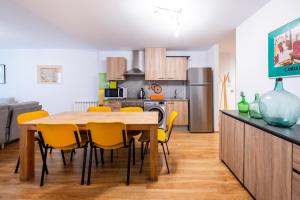 une cuisine avec une table en bois et des chaises jaunes dans l'établissement Apartamento TINTIN en Arinsal, à Arinsal