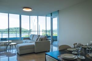 sala de estar con sofá, mesas y ventanas en Oceanview Apt Near Panama City w/ King Bed & More, en Playa Bonita Village