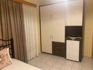 - une chambre avec un lit, une télévision et des armoires dans l'établissement Corali, à Menídion
