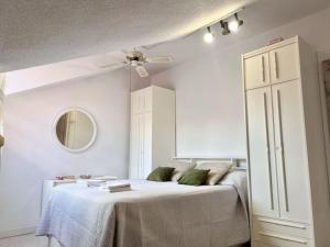 a white bedroom with a bed and a ceiling fan at El Solsticio - 30601 in Somo