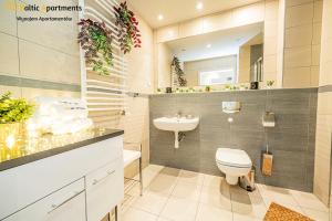 een badkamer met een wit toilet en een wastafel bij Baltic Apartments - Apartament Feniks in Świnoujście