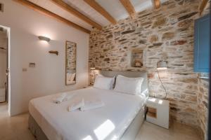a bedroom with a white bed in a stone wall at Alika Resort in Álika