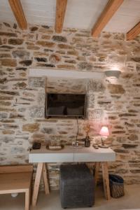 a stone wall with a desk with a television on it at Alika Resort in Álika