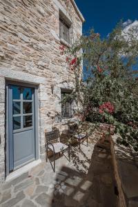 una casa de piedra con una puerta azul y un banco en Alika Resort en Álika