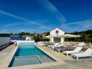 a swimming pool with lounge chairs and an umbrella at Casa do Pátio, casaspensadas in Juncal