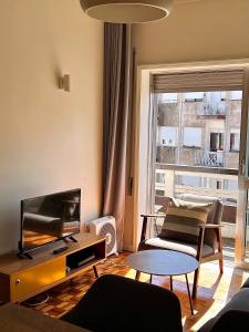 ein Wohnzimmer mit einem Sofa und einem TV in der Unterkunft Oporto Downtown in Porto