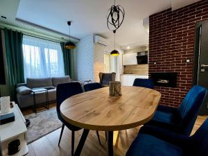 a living room with a wooden table and blue chairs at Apartament Ezuka - Twoje miejsce na mazurach in Giżycko
