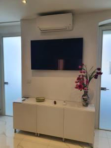 uma sala de estar com televisão e um vaso com flores em MARCO'S HOUSE em Sanremo