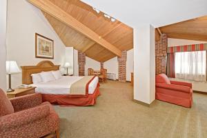 a hotel room with a bed and two chairs at Baymont by Wyndham Indianapolis in Indianapolis