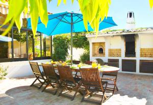Villa Honolulu by Algarve Vacation في ألبوفيرا: طاولة مع كراسي ومظلة زرقاء على الفناء