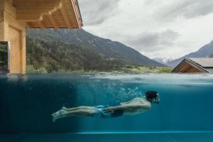 un hombre nadando en un cuerpo de agua en Feelfree Nature Resort, en Oetz