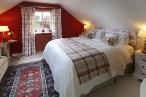 a bedroom with a large bed with red walls at Throphill Grange in Morpeth +11 photos