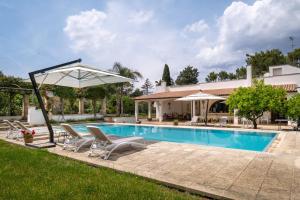 a pool with chairs and an umbrella next to a house at Il Carretto in Monteroni di Lecce
