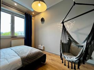 a bedroom with a bed and a hammock at Apartament Ezuka - Twoje miejsce na mazurach in Giżycko