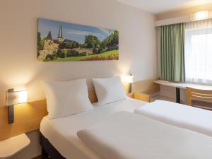 a hotel room with a large bed and a desk at B&B HOTEL Fulda-Hbf in Fulda