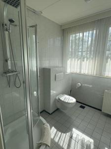 een witte badkamer met een toilet en een douche bij Bed&Breakfast hotel de Greune Weide in Eibergen