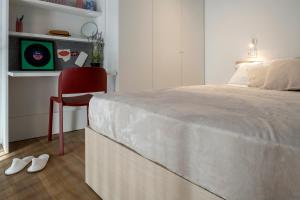 a bedroom with a bed and a red chair at Ripamonti Milan Porta Romana Cosy vibes and modern rooms right around the city centre in Milan
