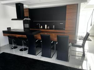 a kitchen with a bar with black counter and stools at Belle Casa Villa in Debrecen