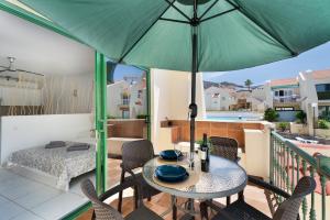 een patio met een tafel en stoelen en een parasol bij Mareverde K131 in Adeje