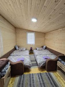two beds in a room with wooden walls at Dedin Konak in Golubac