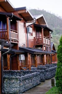 a large wooden building with a stone wall at Etno selo Bok in Vrhpolje