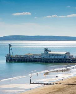 a group of people walking on the beach near a pier at Stylish 2 bedroom town centre flat near beach in Bournemouth