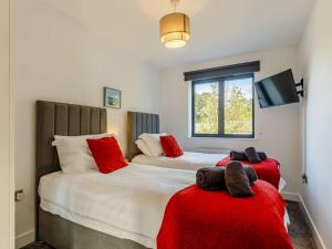 two beds with red pillows in a bedroom at 4 Bed in Bude 89355 in Poughill