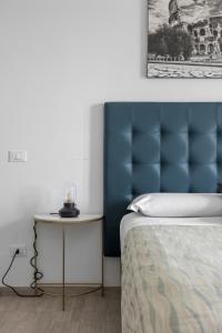 a bedroom with a blue headboard and a side table at SAPIENZA Apartment in Rome