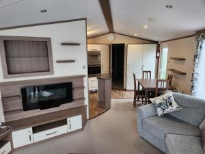 ein Wohnzimmer mit einem Sofa, einem TV und einem Tisch in der Unterkunft The Crown Lodges in Deal
