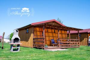 a large wooden cabin with a porch and a chair at Domki przy Akacjowej in Rydzewo