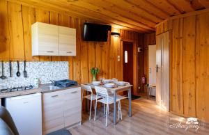 a kitchen with a table with chairs and a stove at Domki przy Akacjowej in Rydzewo