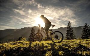 a person riding a bike on a hill with the sun at Haus Piller in Bad Hofgastein