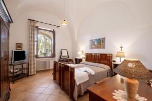 - une chambre avec un lit, une télévision et une table dans l'établissement Il Carretto, à Monteroni di Lecce