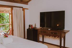 a bedroom with a large flat screen tv on a table at Pousada Cores do Mar Caraíva in Caraíva