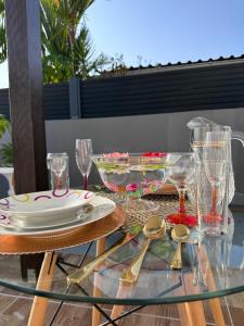 einen Glastisch mit Tellern und Gläsern auf einer Terrasse in der Unterkunft A MO TI KOTE in Guenouillet