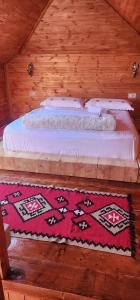 Cama en habitación de madera con alfombra en Silver Hill Guesthouse, en Gjirokastra