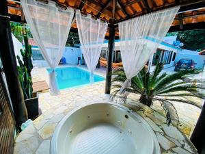 een bad in het midden van een patio met een zwembad bij Casa em Maresias Completa in Maresias