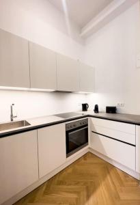 eine weiße Küche mit weißen Schränken und Holzböden in der Unterkunft Exclusive Suite Museumsquartier in Wien