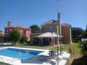 a house with a swimming pool and an umbrella at VILLA DEL MAR in Novo Sancti Petri
