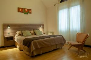 a bedroom with a bed and a chair and a window at Departamentos - Belgrano 810 in San Martín de los Andes