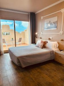 a bedroom with a large bed and a balcony at Hotel Celimar in Sitges