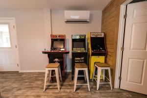 a room with two arcade machines and two stools at Somewhere On A Beach - Dog Friendly • Private Pool • Hot Tub • Fire Pit • Game Room • Horseshoe Pits • Walk to beach, Sound, arcade and go carts! in Kill Devil Hills