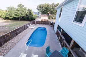 a backyard with a swimming pool and chairs and a house at Somewhere On A Beach - Dog Friendly • Private Pool • Hot Tub • Fire Pit • Game Room • Horseshoe Pits • Walk to beach, Sound, arcade and go carts! in Kill Devil Hills