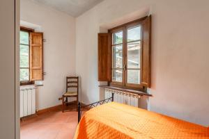 een slaapkamer met een bed en 2 ramen en een stoel bij Casa delle Rose in Borgo a Mozzano