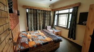 Schlafzimmer mit einem Bett und einem Fenster in der Unterkunft Hostel Inn Srinagar in Srinagar