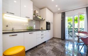 a kitchen with white cabinets and a yellow stool at Cozy Home In Starigrad Paklenica in Starigrad-Paklenica