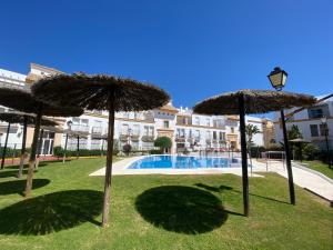 a group of umbrellas in the grass near a pool at Apartamento a pie de playa in Rota