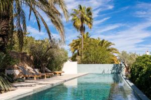 a swimming pool with chaise lounges and palm trees at Boutique Hotel Jardines de Palerm in San Jose