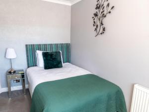 a bedroom with a bed with a green and white blanket at The Kenley Hotel in Blackpool