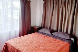 a bedroom with a bed with a red blanket and a window at Arenal TitaHouse in Agua Azul